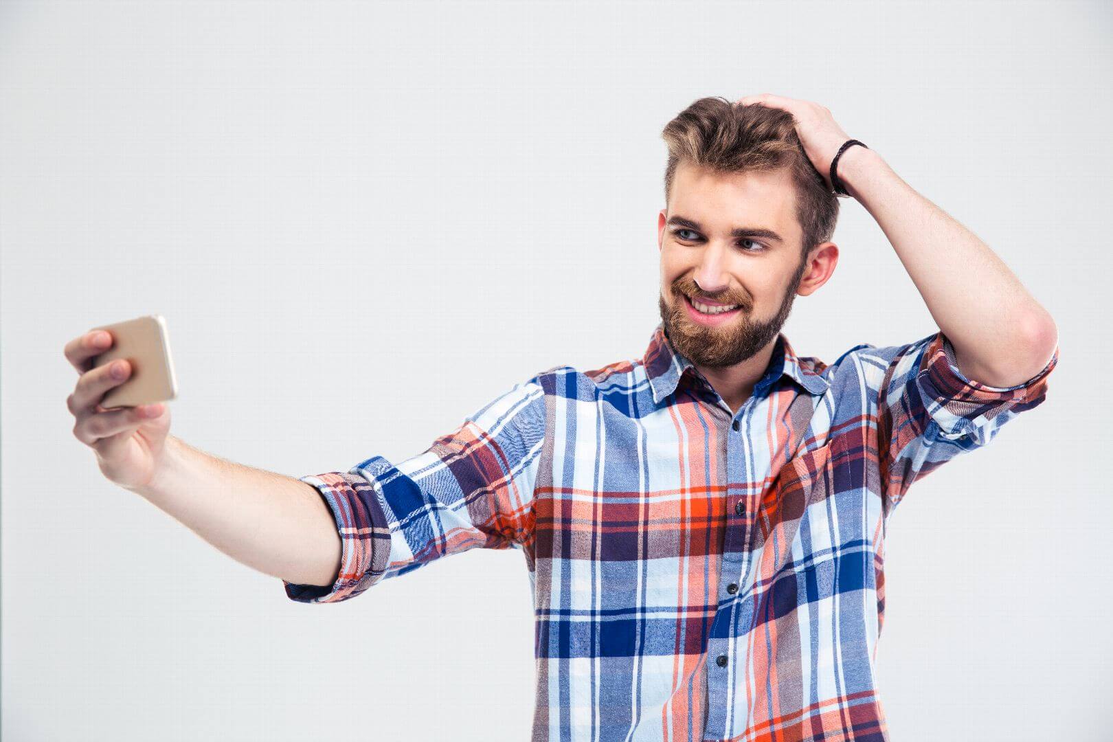 Portrait of a cheerful casual man making selfie photo on smartphone isolated on a white background